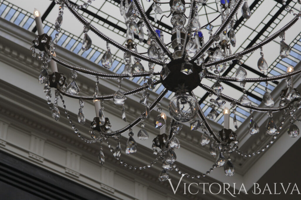 Crystal chandelier detail with stained and leaded glass skylight ceiling